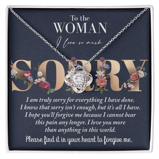 The "Sorry-Bear This Pain - Love Knot Necklace," crafted in 14k white gold with cubic zirconia crystals, comes in a box featuring a heartfelt apology message to a woman, expressing love and remorse.