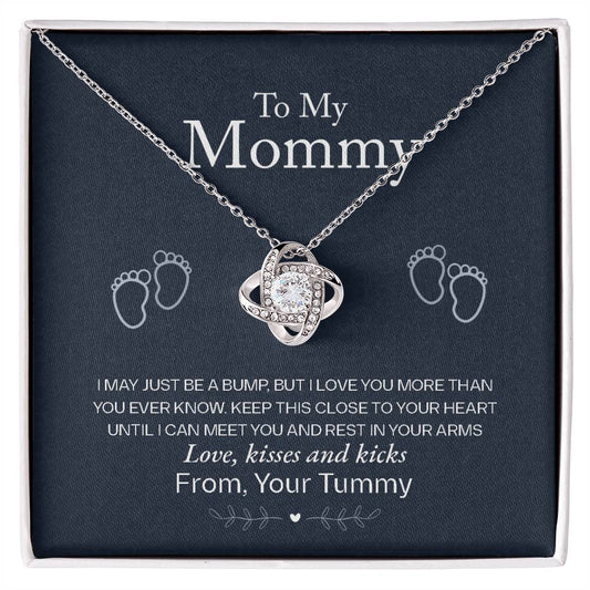 A silver heart-shaped To My Mommy, Love From Your Tummy - Love Knot Necklace by ShineOn Fulfillment, presented in a gift box with baby footprints decoration, for an expectant mother.