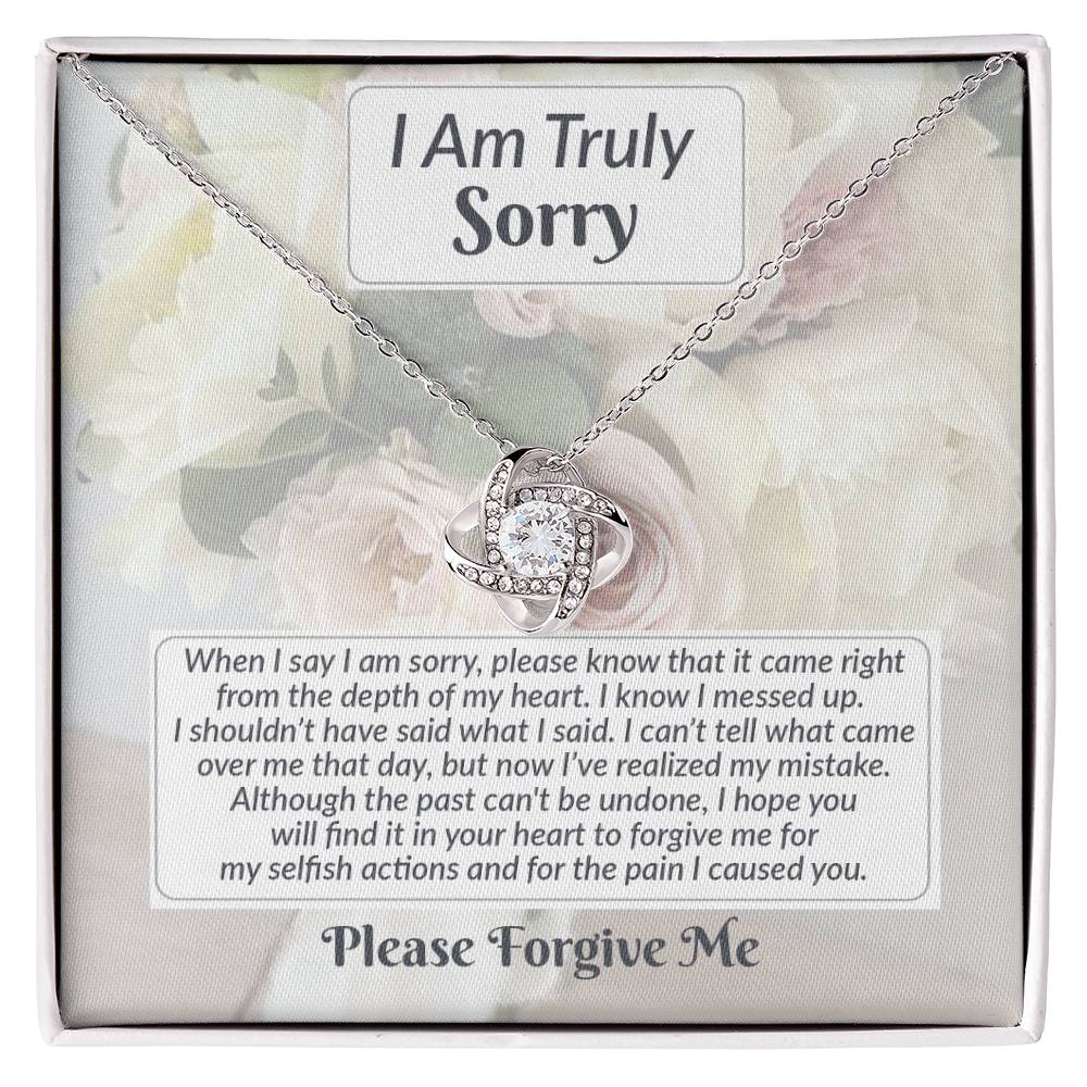 The Sorry-What I Said - Love Knot Necklace comes with a pendant and is elegantly presented in a gift box. The box features a floral background and includes an apology message with the text "I am truly sorry" and "Please forgive me." This thoughtfully crafted piece, made from cubic zirconia, conveys sincere heartfelt remorse.