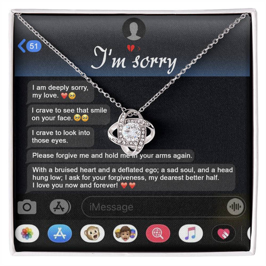 An "I'm sorry" message is displayed on a phone screen along with the stunning Sorry, Rebuild Our Connection - Love Knot Necklace. This necklace, available in either white gold or yellow gold finish and adorned with cubic zirconia crystals, perfectly complements the heartfelt plea for forgiveness.