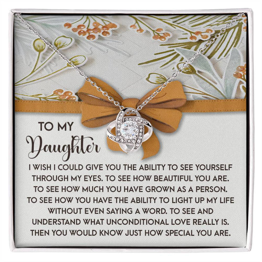 The Daughter-Saying A Word - Love Knot Necklace, embellished with sparkling cubic zirconia crystals, is beautifully displayed against a floral-patterned backdrop. Paired with the touching inscription "To My Daughter," it serves as the perfect personalized gift to express love and admiration.