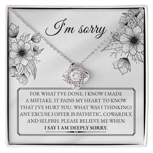 A "Sorry-Made A Mistake - Love Knot Necklace" features a box with a heartfelt apology message. The white gold finish and cubic zirconia crystals shimmer, as the text expresses deep regret and sorrow for causing hurt, describing the actions as pathetic, cowardly, and selfish, pleading for forgiveness.