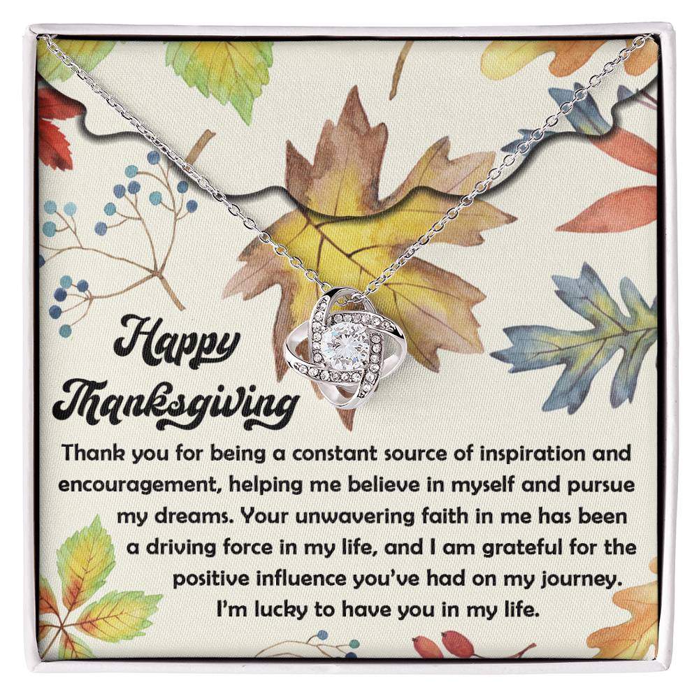 Displayed on a card with a heartfelt Thanksgiving message, the Thanksgiving-On My Journey - Love Knot Necklace glistens amidst colorful autumn leaves—a perfect personalized gift.