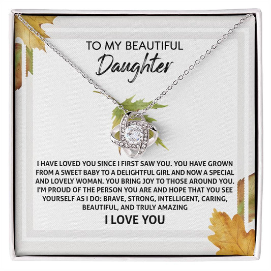 The Daughter-See Yourself - Love Knot Necklace, featuring an interlocking design adorned with cubic zirconia crystals, is showcased in a box that bears a heartfelt message of love and admiration to a daughter.