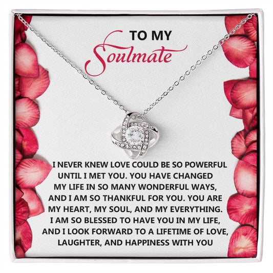 The Soulmate-Until I-Love Knot Necklace, intertwined with delicate cubic zirconia accents, rests elegantly on a white card surrounded by red petals. It features a romantic message about love and gratitude, making it a heartfelt gift.