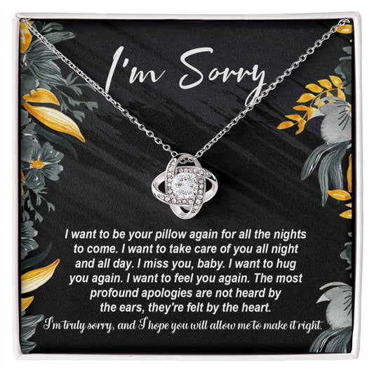 The "Sorry, Be Your Pillow - Love Knot Necklace" features an intertwined heart pendant adorned with cubic zirconia crystals. It comes in a gift box inscribed with "I'm Sorry" and includes a heartfelt apology message expressing regret and a desire for reconciliation.