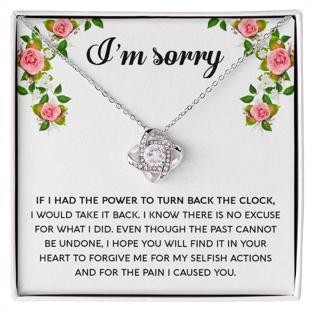 The "Sorry, Make It Right - Love Knot Necklace," featuring a silver intertwined knot pendant adorned with cubic zirconia crystals, is beautifully displayed in a box. The text on the box reads, "I’m sorry," with an apology message below, framed by a floral border in the top corners.