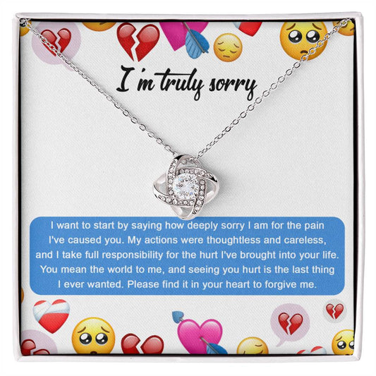 The Sorry-How Deeply Sorry - Love Knot Necklace features a pendant with an intertwined design, adorned with sparkling cubic zirconia crystals. The piece rests on a card that includes an apology message accompanied by various emoticons, such as hearts and sad faces.