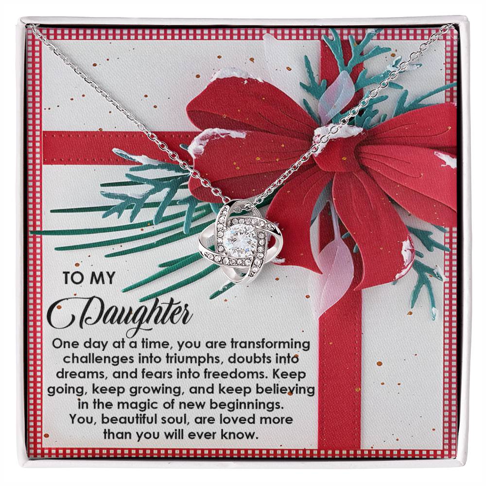 The Daughter-Beautiful Soul - Love Knot Necklace, adorned with sparkling cubic zirconia crystals, is gracefully presented on a card featuring a red bow and an inspirational message for your daughter. This personalized gift is ideal for conveying your heartfelt sentiments.