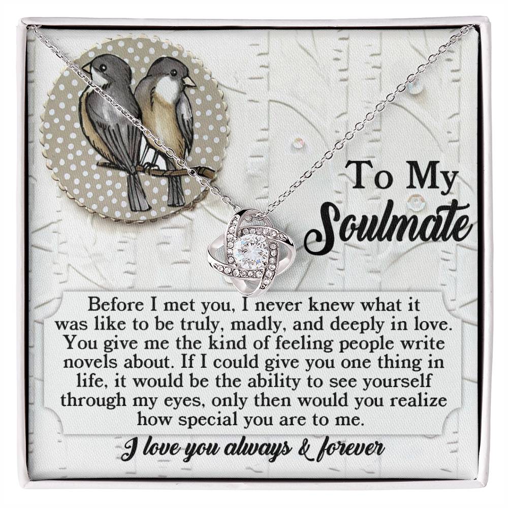 Displayed elegantly on a card that features two birds and the words, "To My Soulmate," the Soulmate-Write Novels - Love Knot Necklace showcases a swirling pendant adorned with sparkling Cubic Zirconia Crystals. The accompanying card contains a heartfelt message expressing love and appreciation.