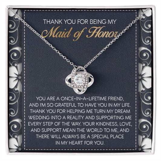 The "To Maid of Honor, World To Me - Love Knot Necklace" features a heart-shaped pendant adorned with Cubic Zirconia Crystals. It comes beautifully packaged in a box that includes an inscribed thank-you note, expressing heartfelt gratitude to the Maid of Honor, making it a perfect personalized gift.