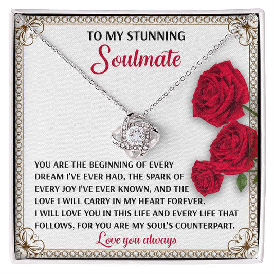 The Soulmate-Soul's Counterpart Love Knot Necklace comes in a gift box surrounded by red roses, featuring a heart pendant adorned with cubic zirconia crystals and a heartfelt message about love and soulmates.