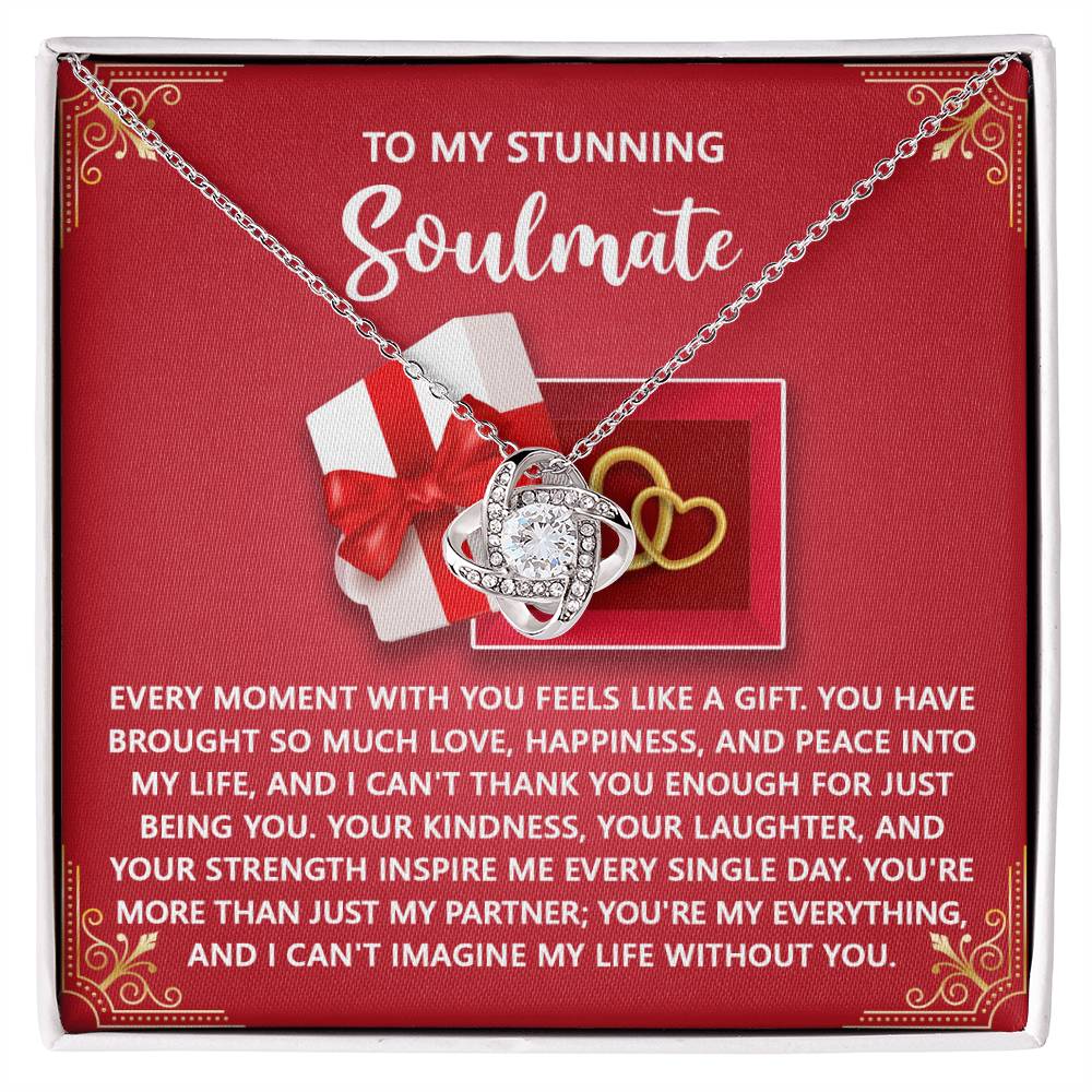 The Soulmate-Like A Gift - Love Knot Necklace is a heart-shaped piece with sparkling cubic zirconia crystals, elegantly set on a red card. It features heartfelt messages of love and appreciation with delightful graphics capturing sincerity.