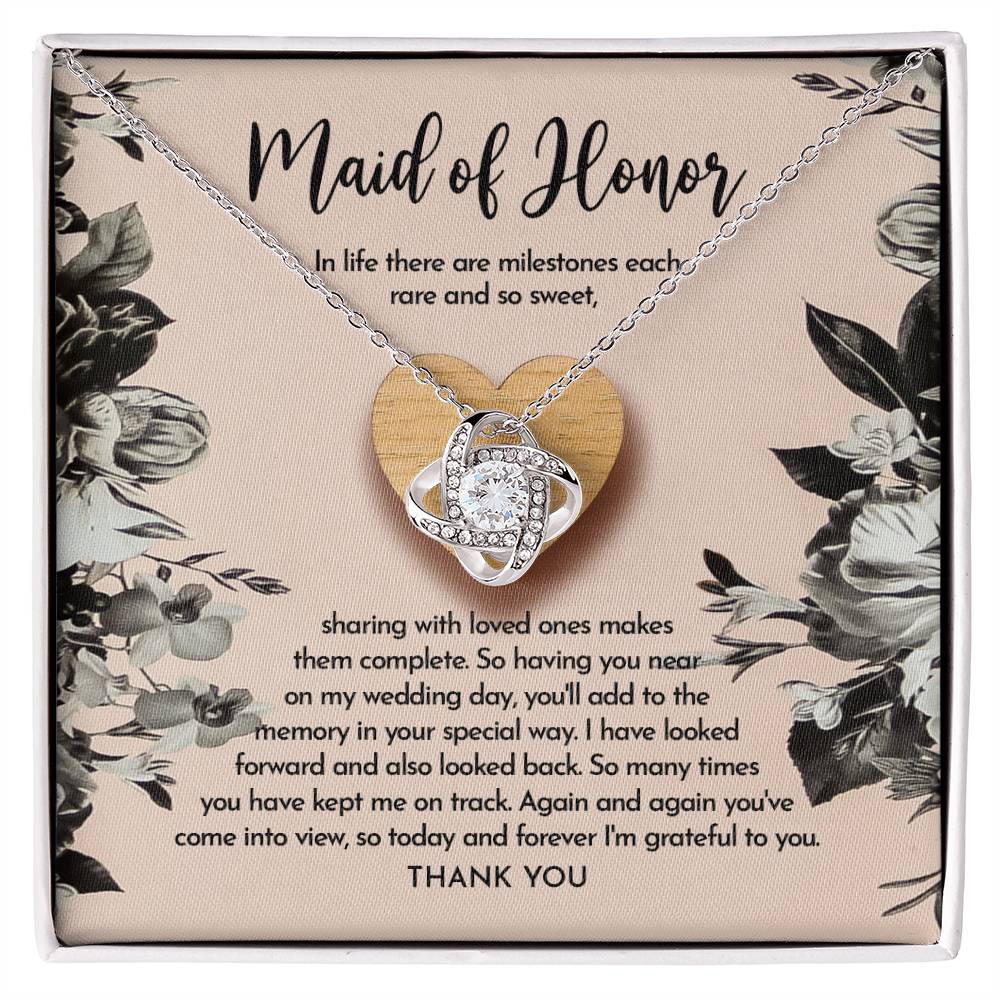 The "To Maid of Honor, My Wedding Day - Love Knot Necklace" features a heart-shaped pendant on a card titled "Maid of Honor," with a heartfelt message about milestones, love, and gratitude. The pendant is available in white gold or yellow gold finish and is adorned with sparkling cubic zirconia crystals.