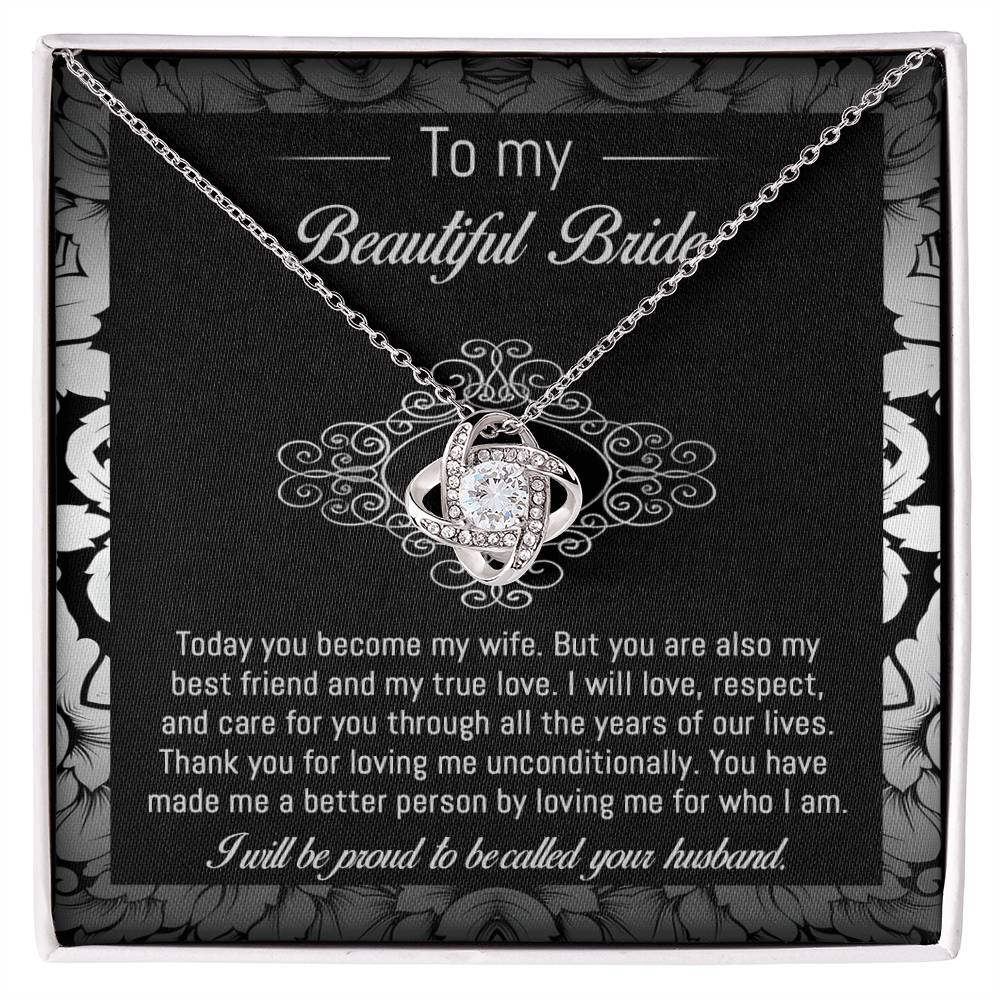 The "To Bride, My True Love - Love Knot Necklace" with a diamond pendant is displayed in a black and white box adorned with a floral pattern. The box, featuring cubic zirconia crystals, includes a heartfelt message addressed to "my beautiful bride" from her husband.