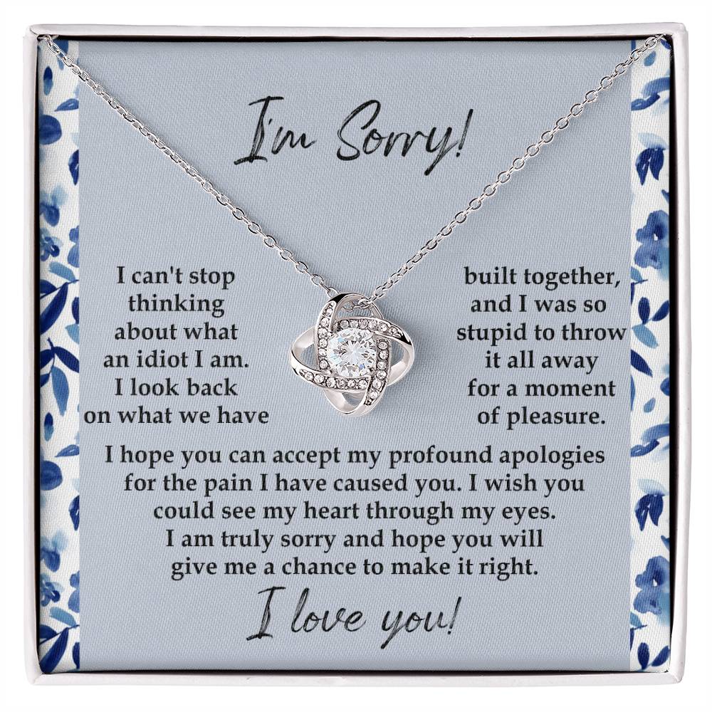 The "Sorry-Through My Eyes - Love Knot Necklace," adorned with cubic zirconia crystals and a white gold finish, is presented on a card featuring a heartfelt apology message, expressing regret for causing pain and seeking forgiveness.