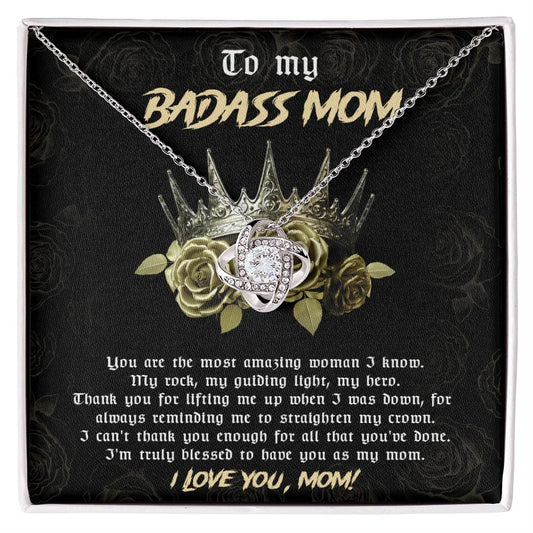 A To Mom, Straighten My Crown - Love Knot necklace with a heart-shaped pendant on a card saying "to my badass mom" with a heartfelt message, inside a black box adorned with gold roses.