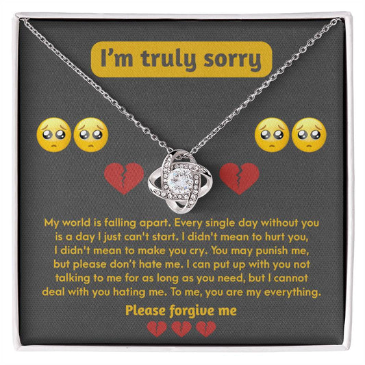 The Sorry-Make You Cry - Love Knot Necklace, featuring an intertwined design, is presented in a box. Crafted from 14k white gold and adorned with cubic zirconia crystals, the box lid conveys a remorseful message with crying face and broken heart emojis, expressing heartfelt apologies and a plea for forgiveness.