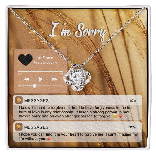 The "Sorry, Person To Forgive - Love Knot Necklace" features a gold finish and sparkling cubic zirconia crystals. It is presented on a card adorned with musical notes and icons that reads "I'm Sorry," along with heartfelt messages of apology and pleas for forgiveness.