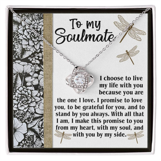 The *Soulmate-Make This Promise - Love Knot Necklace* features a heart pendant adorned with cubic zirconia crystals, presented on a card decorated with floral and dragonfly motifs and conveying a heartfelt message to a soulmate.