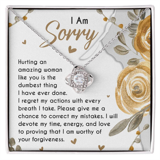 The Sorry-Amazing Woman - Love Knot Necklace, adorned with cubic zirconia crystals, rests in a jewelry box on a heartfelt note that reads, "I Am Sorry. Hurting an amazing woman like you is the dumbest thing I have ever done..." along with more apologetic text.