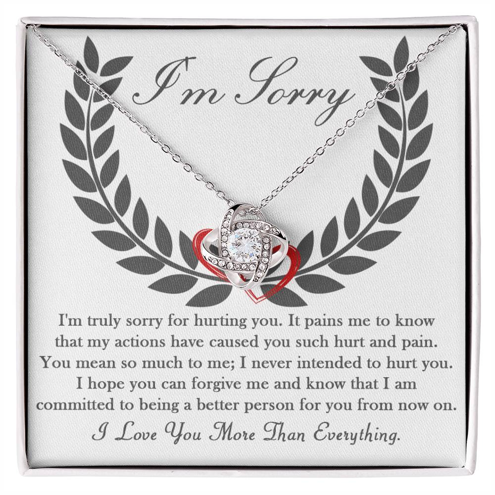 The "Sorry-From Now On - Love Knot Necklace," featuring a white gold finish and adorned with cubic zirconia crystals, is presented in a box. The intertwined heart pendant comes with an apology message, expressing deep regret and a commitment to change for the better.