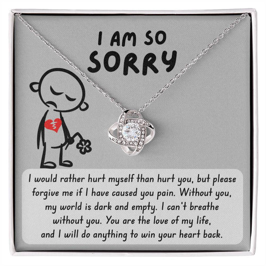 The Sorry-Dark And Empty - Love Knot Necklace, crafted from 14k white gold and adorned with cubic zirconia crystals, comes with a card featuring an illustration of a sad figure with a broken heart and a flower. The card bears an apology message with "I AM SO SORRY" at the top.