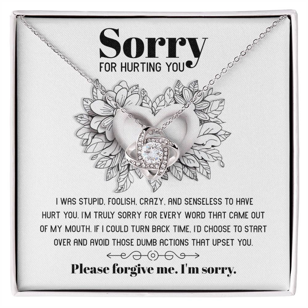 The Sorry-Turn Back Time - Love Knot Necklace, adorned with sparkling cubic zirconia crystals and featuring an intertwined pendant, is displayed on a card with the heartfelt apology message, "Sorry for hurting you," symbolizing an unbreakable bond and a request for forgiveness.