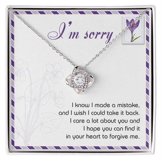 The "Sorry, Take It Back - Love Knot Necklace," featuring a silver pendant embellished with shimmering cubic zirconia crystals, is presented on a sympathy card that reads, "I'm sorry. I know I made a mistake, and I wish I could take it back. I care a lot about you and hope you can forgive me.