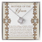 To Mom Of Groom, New Mother - Love Knot Necklace with an interlocking heart pendant, adorned with cubic zirconia crystals, on a card reading: “Mother of the Groom” and a heartfelt message appreciating the groom's mother. Available in white gold or yellow gold finish.