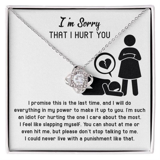 A box containing the Sorry-Stop Talking - Love Knot Necklace and an apology note that reads, "I’m Sorry That I Hurt You," accompanied by a promise to make amends. The necklace features a central design adorned with embedded cubic zirconia crystals and a white gold finish, intending to mend bridges and spark new beginnings.