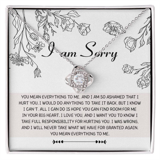 Introducing the "Sorry-Your Big Heart - Love Knot Necklace": This exquisite white gold necklace showcases an elegant intertwined heart design, adorned with shimmering cubic zirconia crystals. It comes complete with a heartfelt card that reads, "I am Sorry," followed by an apologetic message. The entire set is beautifully presented in a floral-printed box.