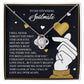 The Soulmate-Look At You Love Knot Necklace, a silver piece with a gold finish, rests on a black and gold backdrop. It features romantic motifs of hearts and an arrow, and its cubic zirconia pendant symbolizes endless love.
