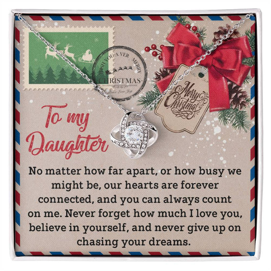 The Daughter-Forever Connected - Love Knot Necklace, featuring a cubic pendant embellished with sparkling cubic zirconia crystals, is elegantly presented on a holiday-themed card. The card contains a heartfelt message to a daughter about love, connection, and perseverance, making it a truly personalized gift.