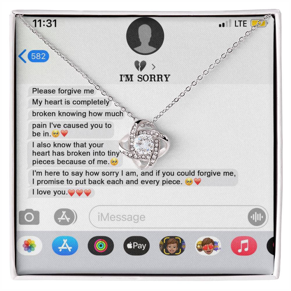 The "Sorry, Completely Broken - Love Knot Necklace" features a gold finish and sparkling cubic zirconia crystals, displayed atop a printed text message conversation that conveys an apology and expresses love.