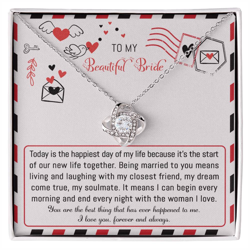 The "To Bride, The Happiest Day - Love Knot Necklace," beautifully crafted from 14k white gold and adorned with cubic zirconia crystals, is elegantly presented in a box featuring a heartfelt message for the bride, expressing love and joy for their life together.