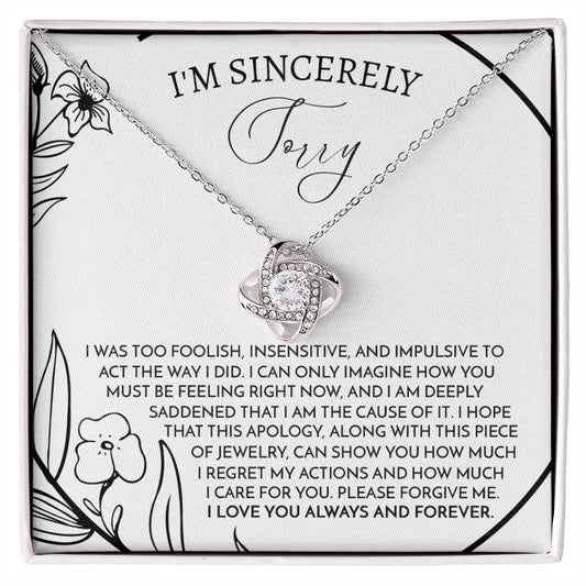 The Sorry-Care For You - Love Knot Necklace features a pendant with intertwined loops adorned with sparkling cubic zirconia crystals. It is elegantly displayed on a card that conveys an apology message, reading "I'm sincerely sorry," expressing deep regret and love.