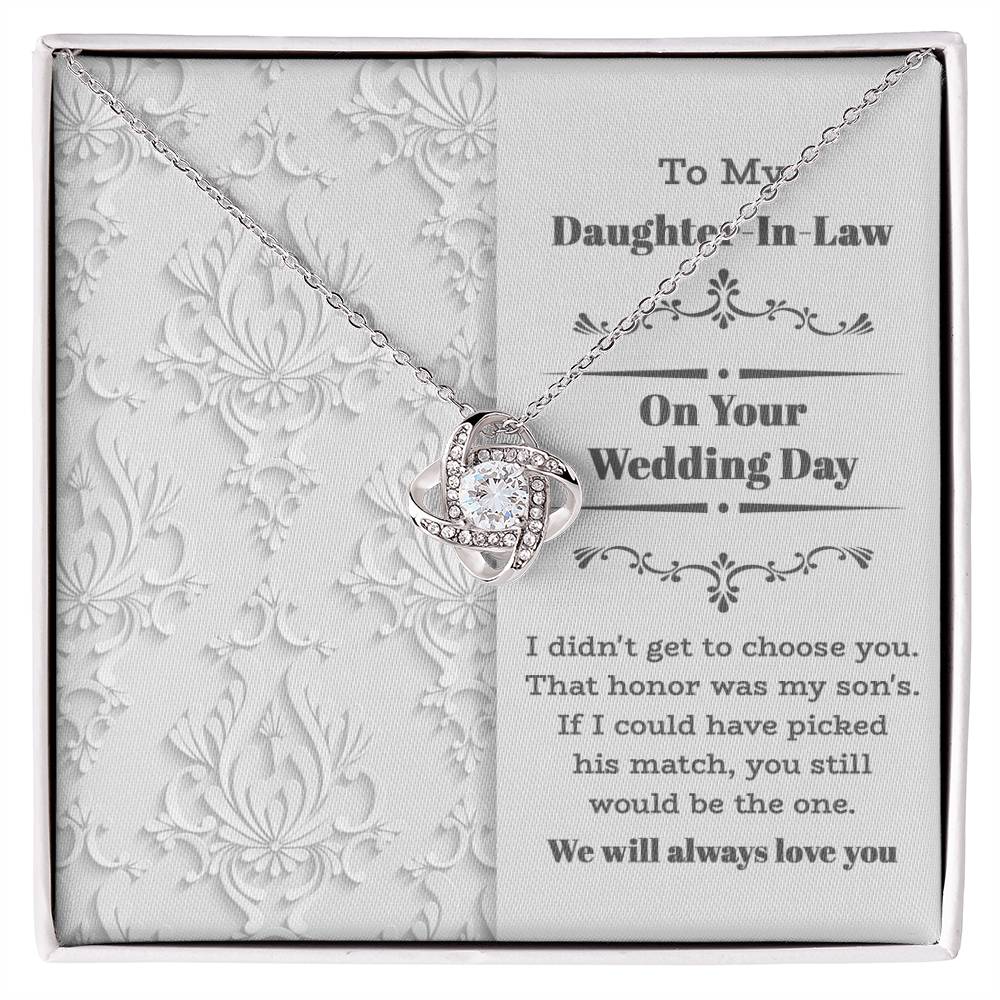 To My Daughter-In-Law Wedding, Be The One - Love Knot Necklace with an intertwined heart design, adorned with cubic zirconia crystals, displayed on a decorative backing card. The card reads: "To My Daughter-In-Law On Your Wedding Day" with a sentimental message below. Perfect as a gift for a loved one.