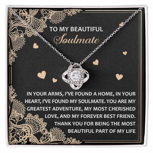 The Soulmate-Beautiful Part Love Knot Necklace features an interlocking heart pendant with a white gold finish, elegantly presented on a black card with a heartfelt message about love. Embedded with cubic zirconia crystals, it symbolizes timeless bonds and eternal affection.