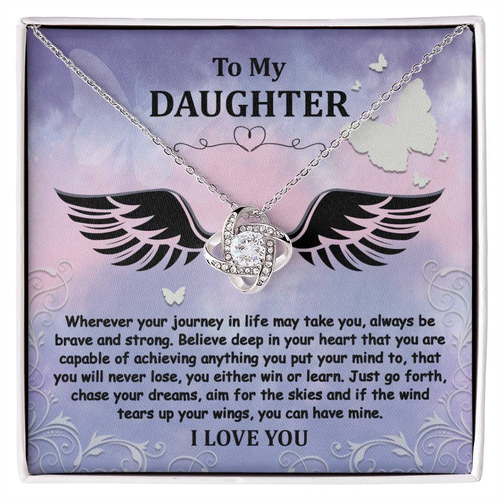 The "To Daughter, Brave And Strong - Love Knot Necklace" features a gold finish and a Cubic Zirconia pendant, beautifully displayed in a box. The box contains a heartfelt message titled "To My Daughter," encouraging bravery, strength, and the pursuit of dreams, and concludes with the words "I LOVE YOU.