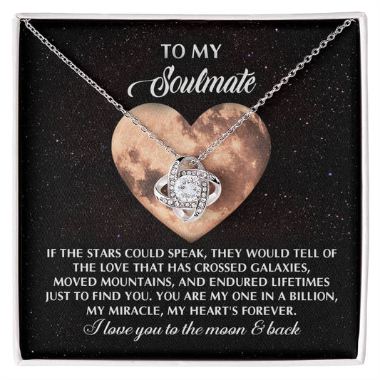 The Soulmate-Crossed Galaxies Love Knot Necklace features a heart and moon card background. It reads, "To my soulmate...I love you to the moon & back." Crafted with cubic zirconia crystals, it represents our unbreakable bond.