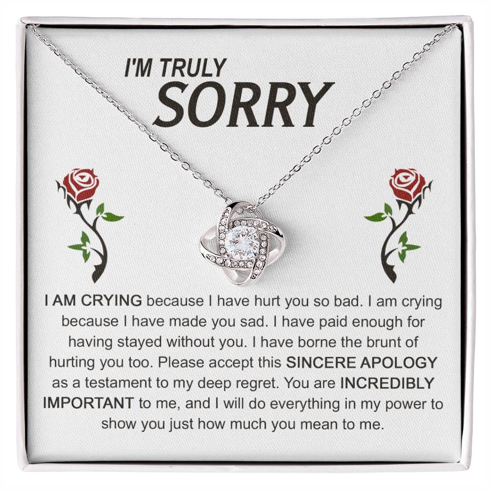 The Sorry-Made You Sad - Love Knot Necklace, crafted in silver with an interlocking design, is presented on a card featuring an apology message and accompanied by two red roses. The text conveys profound regret and vows to make things right, while the cubic zirconia crystals enhance the elegance of this heartfelt gesture.