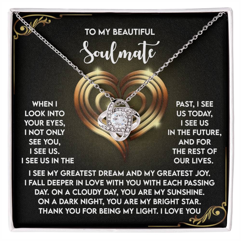 The Soulmate-I See Us - Love Knot Necklace features a silver heart-shaped pendant with sparkling cubic zirconia crystals, elegantly displayed on a black background. A romantic message is beautifully inscribed in white text around it.