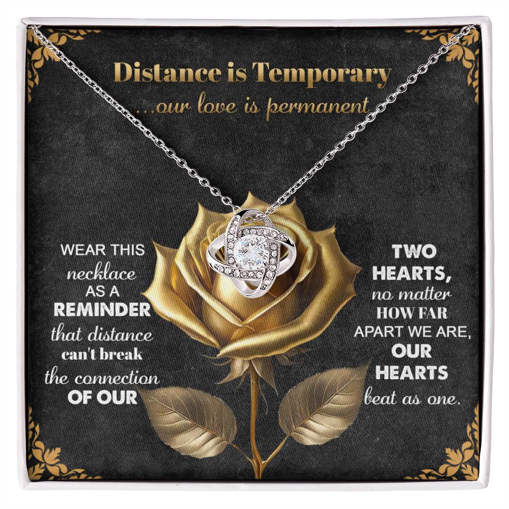 The Soulmate-Love Is Permanent - Love Knot Necklace boasts an intertwined pendant with cubic zirconia crystals, displayed on a rose-designed card with a touching message about distance and love.