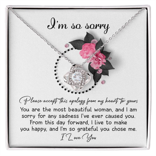 The Sorry-Make You Happy - Love Knot Necklace features a heart-shaped pendant adorned with cubic zirconia crystals, presented in a box decorated with pink flowers and the heartfelt text "I'm so sorry" at the top.