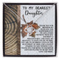 The Daughter-Love And Pride - Love Knot Necklace showcases a beautiful gold finish adorned with cubic zirconia crystals. It comes displayed on a card with the heartfelt message "To My Dearest Daughter," expressing love, gratitude, and the joy she brings.