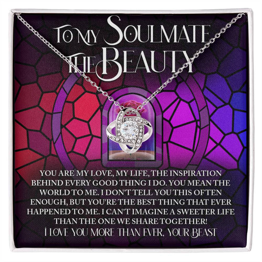 The Soulmate-Sweeter Life - Love Knot Necklace features a gold finish with sparkling cubic zirconia crystals, displayed against a colorful background. Accompanying text celebrates a soulmate with affectionate messages.