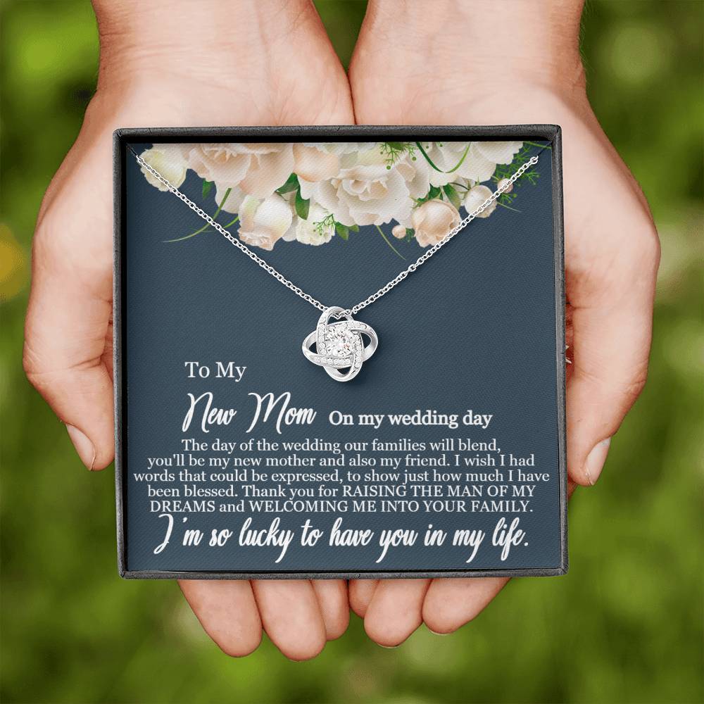 A pair of hands holding a premium gift box containing a "To My New Mom - I am so lucky to have you in my life" Love Knot Necklace with a pendant, featuring an emotional message dedicated to a mother on her wedding day by ShineOn Fulfillment.