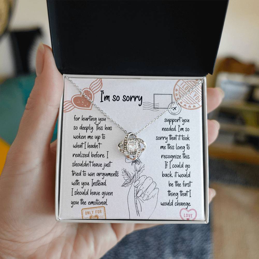 The Sorry-Emotional Support - Love Knot Necklace, featuring an intertwined knot pendant adorned with cubic zirconia crystals, is displayed on a card with an apology message expressing regrets and promising better emotional support in the future.