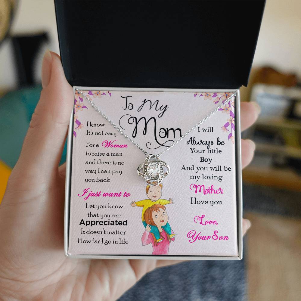 An open jewelry box revealing a ShineOn Fulfillment To My Mom, I Will Always Be Your Little Boy - Love Knot Necklace and a heartfelt printed message to a mother from a son.